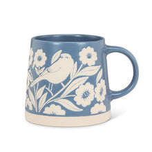 Load image into Gallery viewer, Wide-base blue stoneware mug with ivory bird, leaves, and floral motif and a natural clay base, shown on a white background
