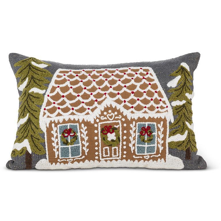 Rectangular tufted lumbar pillow featuring a gingerbread house with snowy trees on a charcoal background