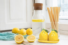 Load image into Gallery viewer, Ceramic lemon-shaped salt and pepper shaker set with green leaf details on a matching yellow tray
