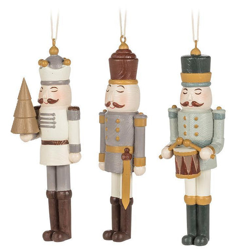 Neutral nutcracker ornaments—Tree, Sword, and Drummer styles—resin with antique-gold accents.
